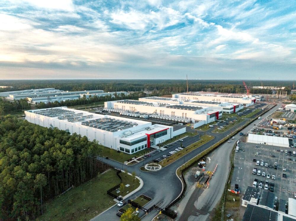 Aerial view of a large distribution and data center facility with an extensive white roof