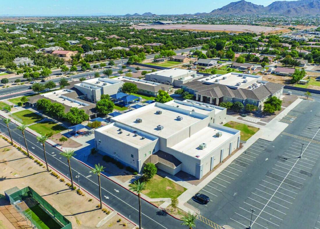 Aerial view of a low-rise commercial campus with large flat white membrane roofs and rooftop HVAC units
